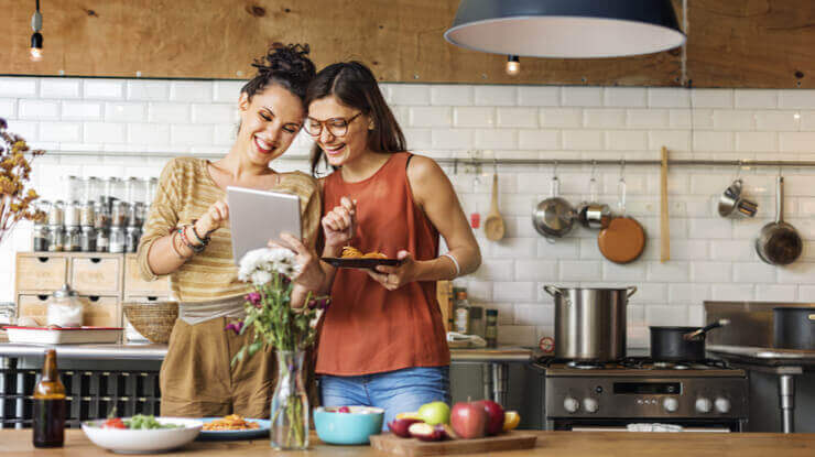 image shows two women in the kitchen looking at natural gas rates online in Georgia